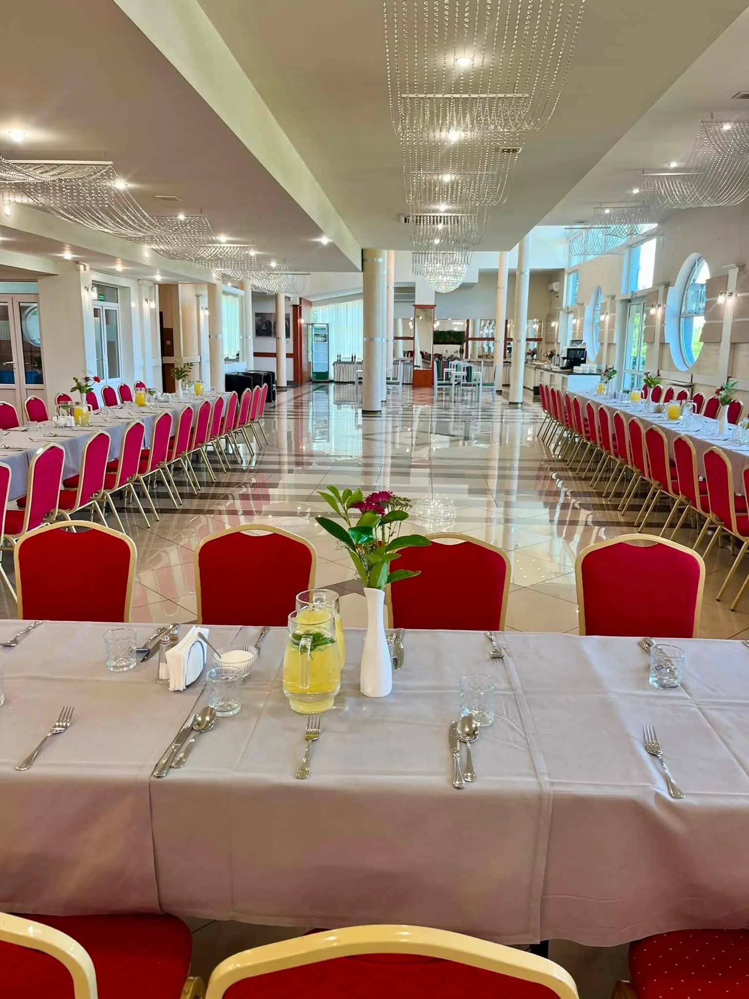 Długie stoły z czerwonymi krzesłami w Restauracji Szkiełka, przygotowane na przyjęcie korpusu dyplomatycznego